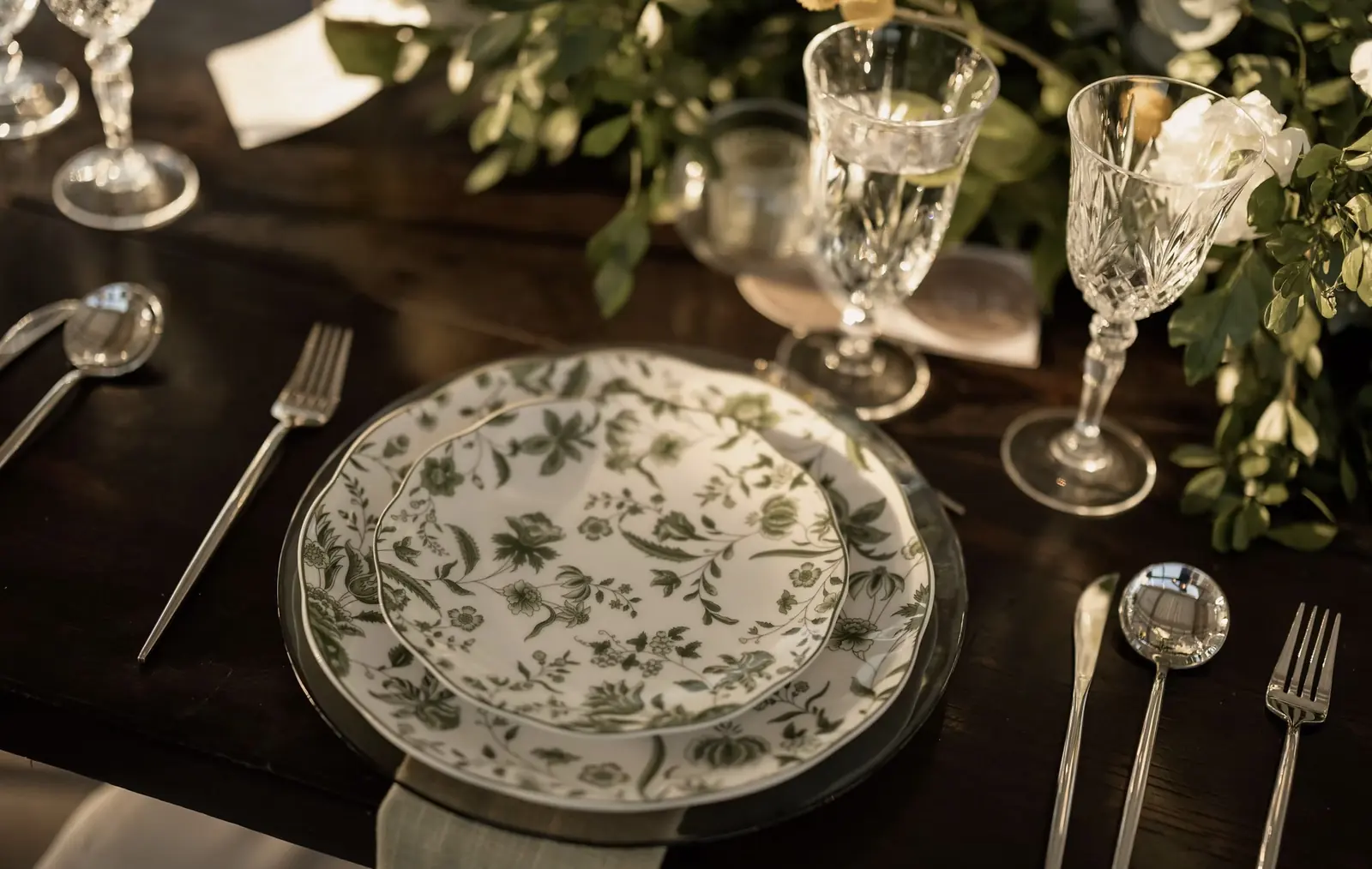 Mesa vestida con mantel de lino verde olivo, vajilla verde y cristalería tallada
